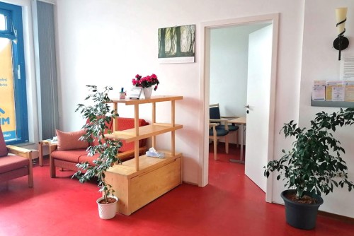 Ein Raum mit einem roten Boden, einigen Pflanzen und einigen Sitzgelegenheiten.