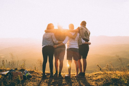 4 Menschen laufen armumschlungend in den Sonnenuntergang